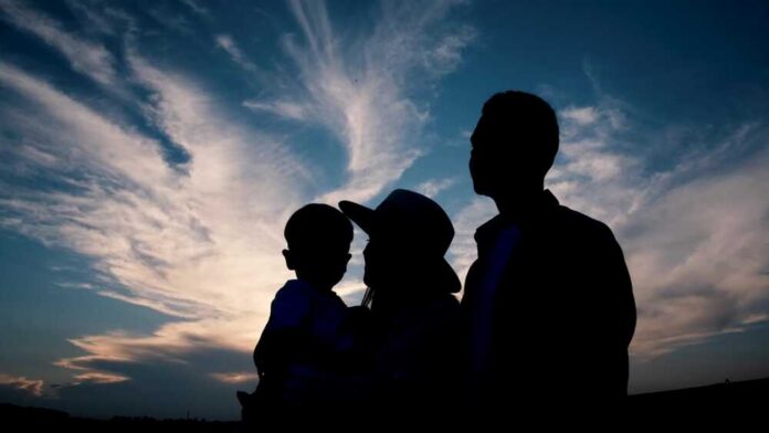 Silhouette of a family against a colorful sunset sky