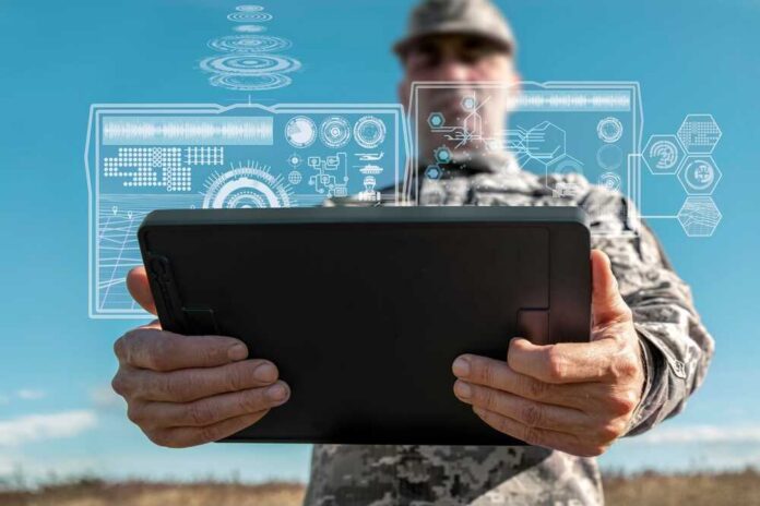 A soldier holding a tablet displaying digital data overlays