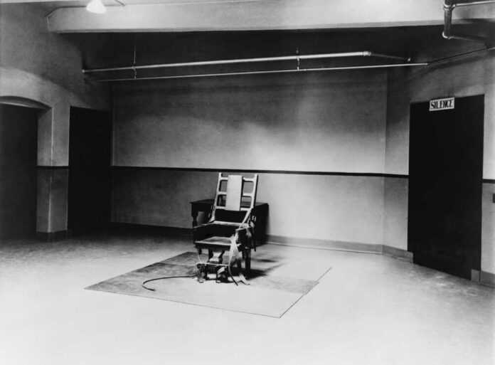 Death,Chamber,And,Electric,Chair,At,Sing,Sing,Prison,In Interior view of a courtroom with wooden benches and large murals
