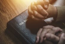 MAGA Pastor Implodes—Endorsement Vanishes Two hands clasped in prayer over a Holy Bible