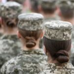 Soldier and child holding hands with American flag