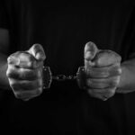 ICE Arrest, Yet Maryland Kept Him on Voter Rolls Hands holding handcuffs in a black and white image
