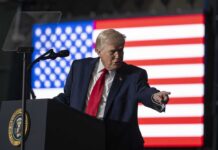Trump Torches Congress Over Iran Vote A man in a suit gestures while speaking at a podium with an American flag in the background