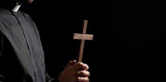 Clergyperson holding a wooden cross