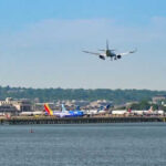 Airplane landing at busy airport near water