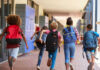 Children with backpacks running in a school corridor
