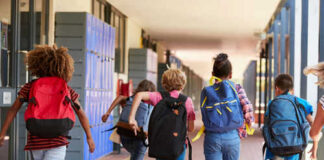 Children with backpacks running in a school corridor