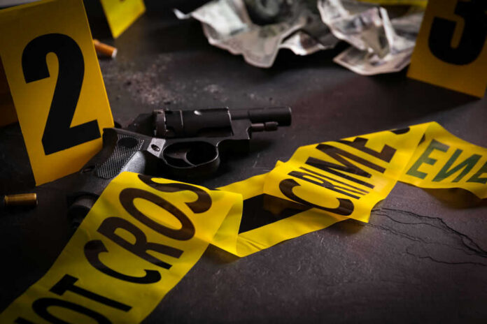 shooting_430056778 Gun surrounded by crime scene tape and evidence markers
