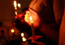 Twin Quakes Turn City Into Tomb Hands holding lit candles in a dark setting