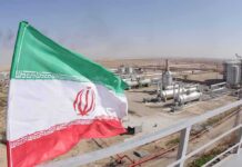 Gulf Hits? Trump Taps Iran’s Stash Iran flag over an oil and gas facility in a desert landscape