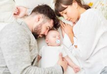Parents sleeping beside newborn baby