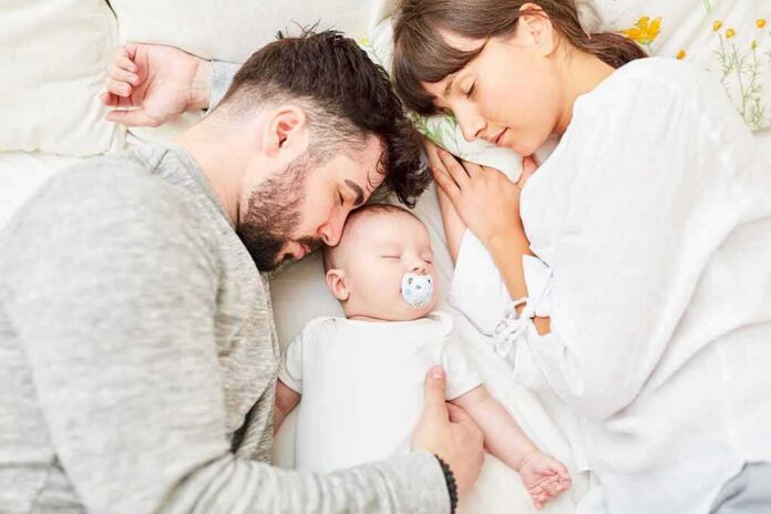 Parents sleeping beside newborn baby