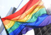 Taxpayer Showdown Over Trans Surge A vibrant rainbow flag waving against a city backdrop