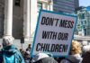 Parental Rights Collision—Education Dept Steps In protest sign held in a crowd outside a government building