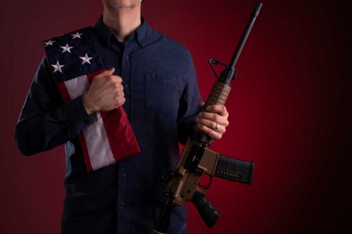 A,Man,Holding,An,Ar-15,Rifle.,An,American,Flag,Is Speaker at podium raising a fist during a conference