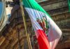 Mexican flag waving in front of an ornate stone building
