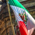 Mexican flag waving in front of an ornate stone building