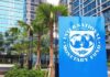 War And Oil Squeeze—IMF Cuts Growth Sign of the International Monetary Fund in front of a modern building with palm trees