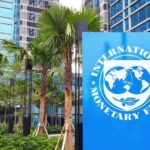 Sign of the International Monetary Fund in front of a modern building with palm trees