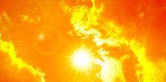 Thermometer displaying high temperature against a sunset city skyline