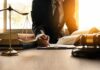 Lawyer writing at desk with scales and gavel