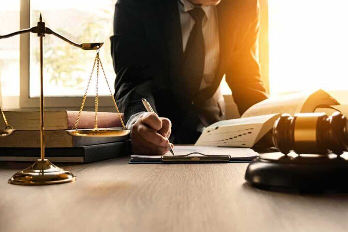 shutterstock_1029430792 Lawyer writing at desk with scales and gavel
