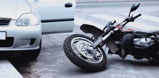 Motorcycle lying on the street beside a car with an open door