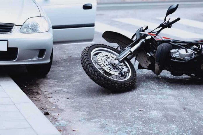shutterstock_1032179767 Motorcycle lying on the street beside a car with an open door
