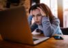 Free Speech Landmine Near Clinics? Woman holding head while looking at laptop