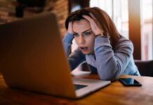 Free Speech Landmine Near Clinics? Woman holding head while looking at laptop
