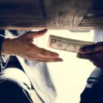Political Violence Cash — Tax Shields at Risk Hands exchanging cash under a table