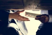 Political Violence Cash — Tax Shields at Risk Hands exchanging cash under a table