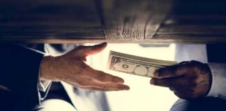 Hands exchanging cash under a table