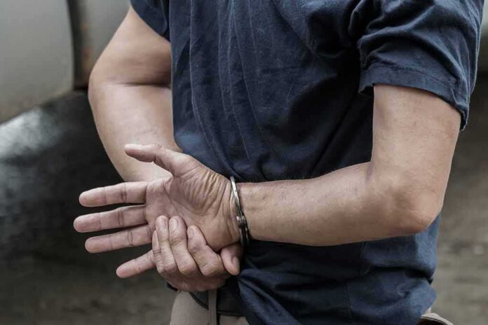 shutterstock_1115333126 person in handcuffs with hands behind back