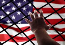 ICE Hunger Strikes Meet Restraints Hand reaching through fence toward American flag