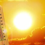 thermometer in front of a blazing sun and orange sky