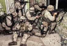 Trump-Era Push Turbocharges Robot Logistics soldiers in camouflage gear take positions inside a damaged building