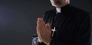 Clergyman in black robe praying with hands together