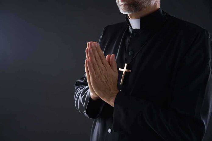 Clergyman in black robe praying with hands together