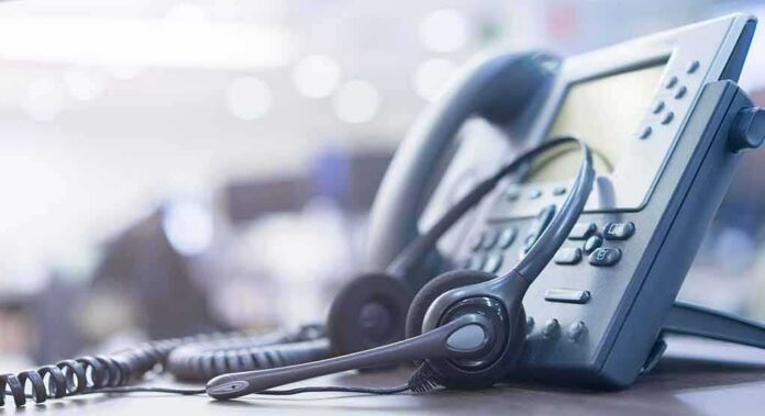shutterstock_1248023887 Headset resting on an office desk phone