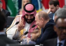 Two delegates converse at an international summit table