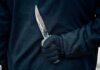 Luxury Co-Op Stabbing Shocks Manhattan Gloved hand holding a serrated knife against a dark jacket