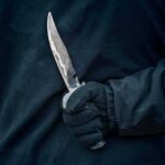 Luxury Co-Op Stabbing Shocks Manhattan Gloved hand holding a serrated knife against a dark jacket