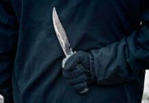 Luxury Co-Op Stabbing Shocks Manhattan Gloved hand holding a serrated knife against a dark jacket