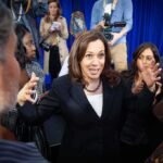 Woman in black blazer speaking animatedly to a crowd