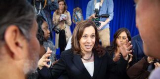 Woman in black blazer speaking animatedly to a crowd