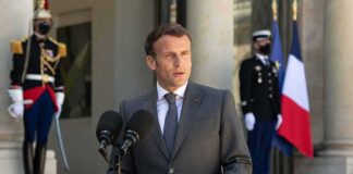 man in suit speaking at podium with microphones