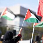 Buried Together — The Strike That Vanished Generations Person waving a Palestinian flag at a rally