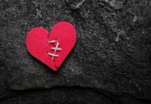 $6.2B Divorce Spiral: Police—Again, And Again red heart with stitches on dark stone background