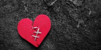 red heart with stitches on dark stone background